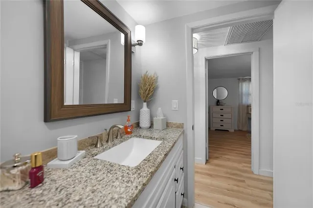 a en suite bathroom with a granite countertop sink and a mirror