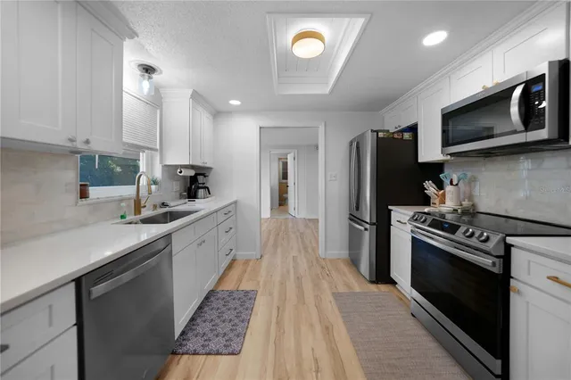 a large kitchen with stainless steel appliances granite countertop a stove a sink dishwasher and a refrigerator with wooden floor