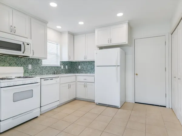 a kitchen with white cabinets and white appliances