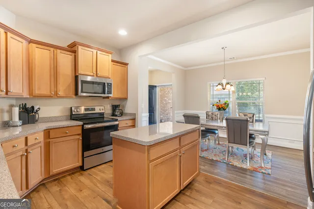 a kitchen with stainless steel appliances granite countertop a stove top oven a sink dishwasher a dining table and chairs with wooden floor