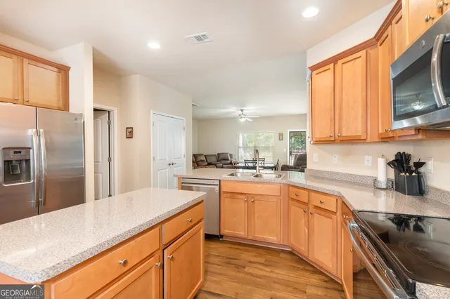 a kitchen with stainless steel appliances granite countertop a sink a stove a refrigerator cabinets and a counter top space