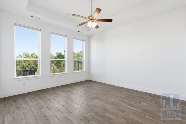 an empty room with wooden floor and windows