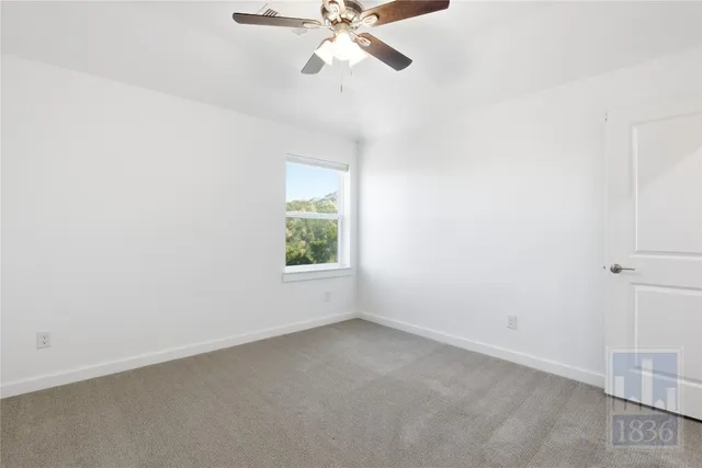 an empty room with a window and a fan