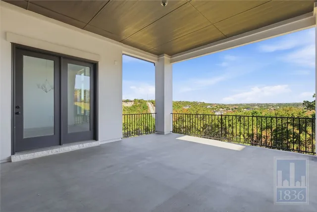a view of an empty room with a balcony and garden