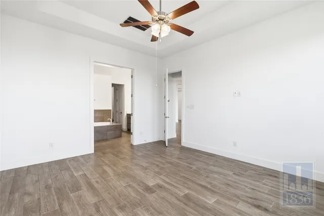 a view of an empty room with window and a ceiling fan