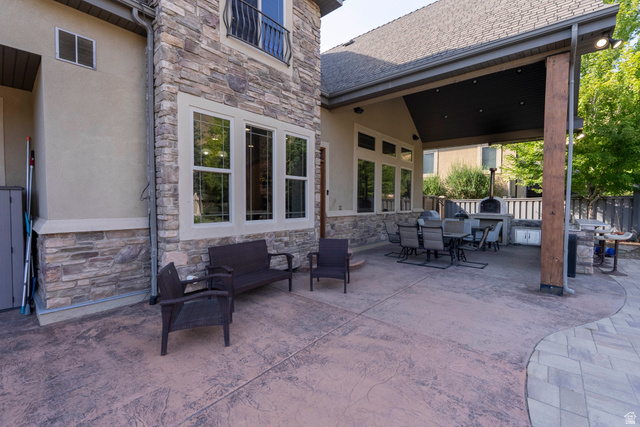 687 South 2080th Street East Springville, UT 84663 - Photo 114 of 149 Expansive stamped concrete patio featuring a covered outdoor kitchen area with built-in pizza oven, exterior stone accents, and large windows