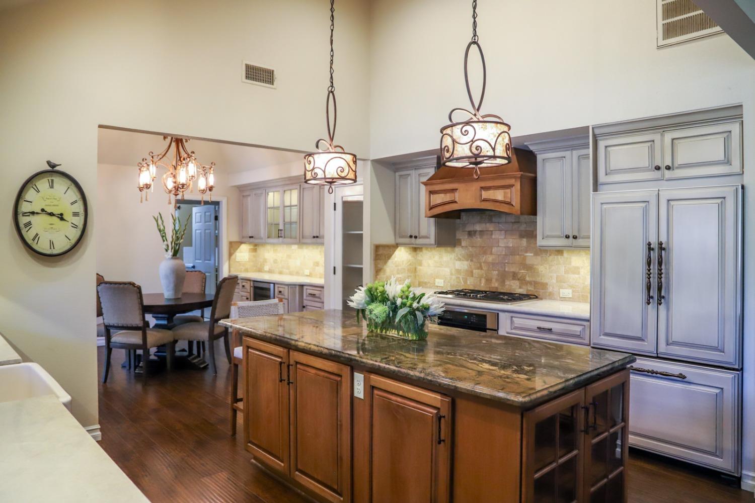 7322 North Geraldine Avenue Fresno, CA 93711 - Photo 4 of 36 a kitchen with kitchen island granite countertop a table and a chandelier