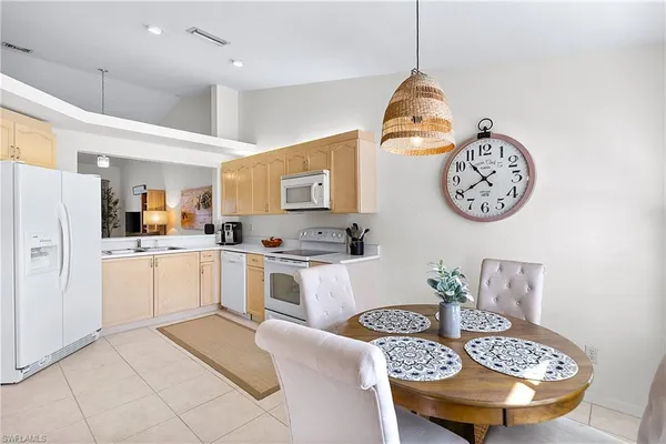 a kitchen with stainless steel appliances granite countertop a sink a stove a refrigerator a dining table and chairs with wooden floor
