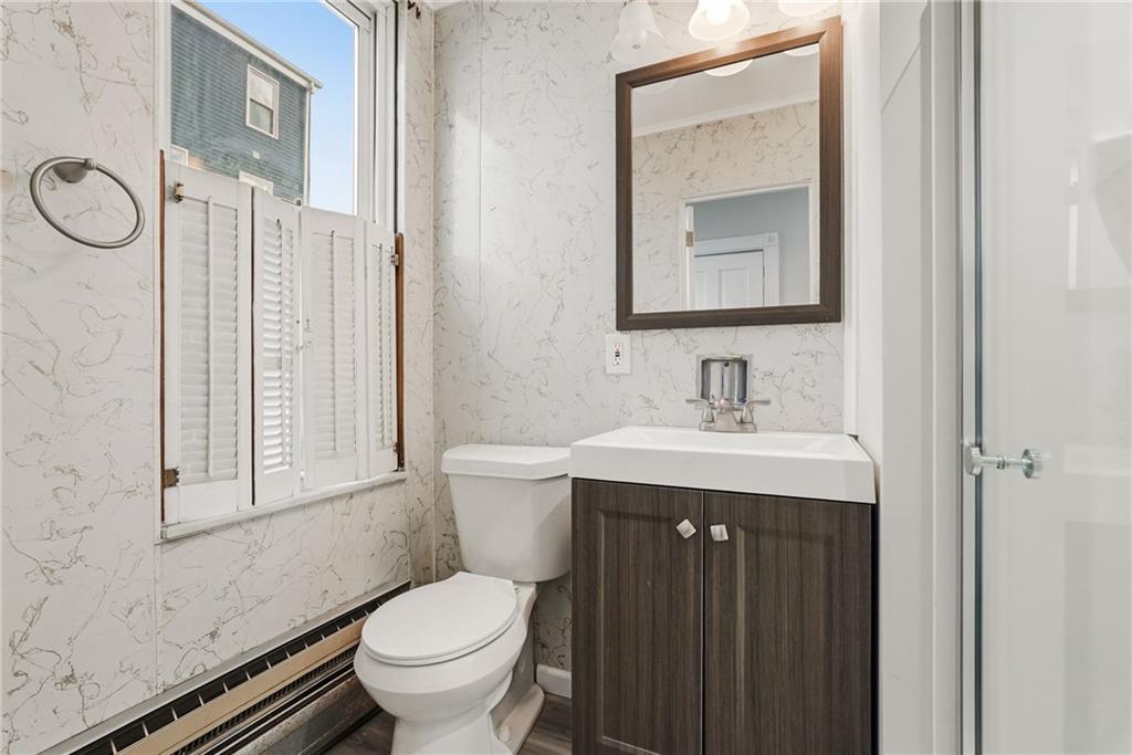 3468 Ligonier Street Pittsburgh, PA 15201 - Photo 19 of 33 a bathroom with a granite countertop toilet a sink a mirror and a window