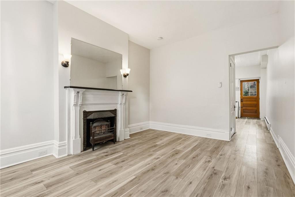 3468 Ligonier Street Pittsburgh, PA 15201 - Photo 5 of 33 a view of an empty room with wooden floor fireplace and a window