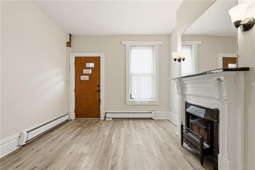 3468 Ligonier Street Pittsburgh, PA 15201 - Photo 6 of 33 an empty room with wooden floor a fireplace and windows