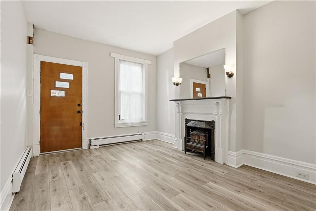 3468 Ligonier Street Pittsburgh, PA 15201 - Photo 7 of 33 an empty room with wooden floor fireplace and windows