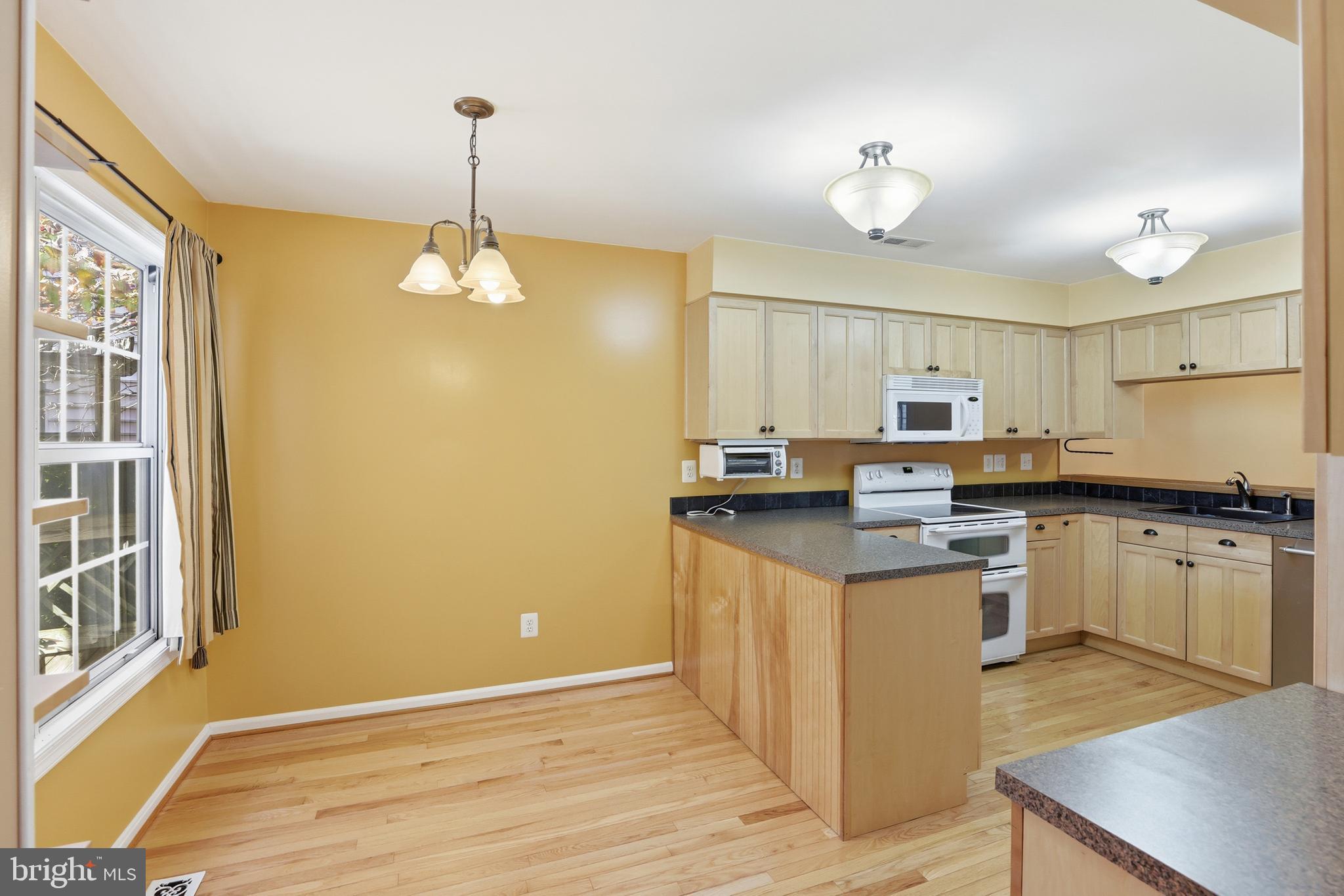 8341 Marketree Circle Montgomery Village, MD 20886 - Photo 11 of 43 a kitchen with kitchen island granite countertop a sink cabinets and wooden floor