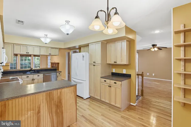 a kitchen with stainless steel appliances granite countertop a refrigerator a stove and a sink with wooden floor