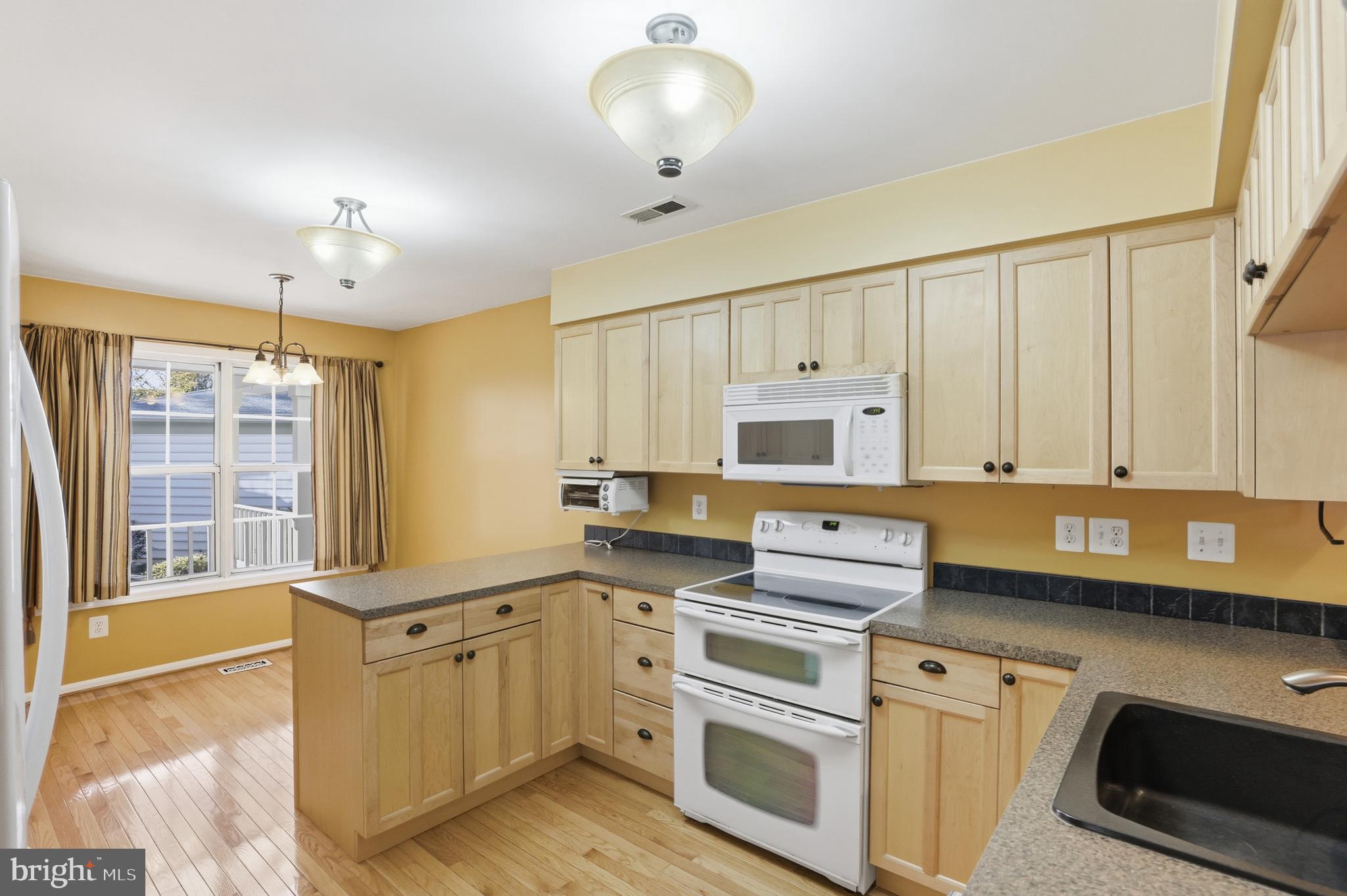 8341 Marketree Circle Montgomery Village, MD 20886 - Photo 14 of 43 a kitchen with stainless steel appliances a stove a sink cabinets and a window