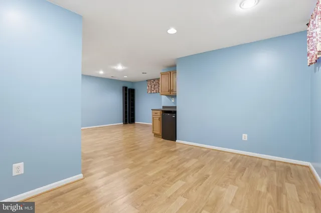 a view of empty room with wooden floor and kitchen