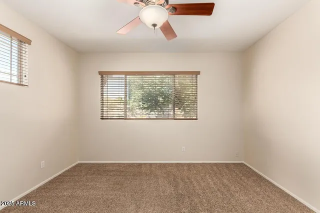 an empty room with a window and a fan