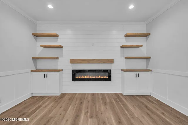 a view of an empty room with wooden floor kitchen view