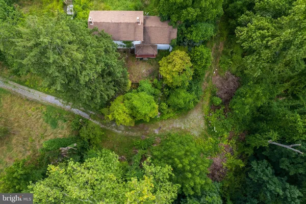 an aerial view of residential house with outdoor space and trees all around