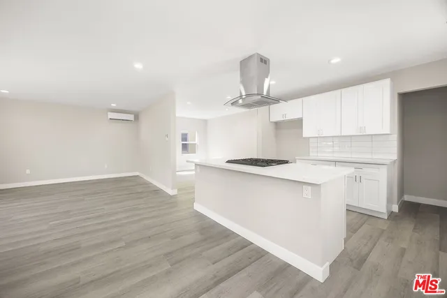 a large kitchen with stainless steel appliances a large counter top a sink and a wooden floors