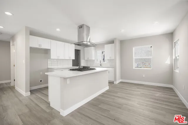 a large kitchen with stainless steel appliances a large counter top a sink a refrigerator and a stove