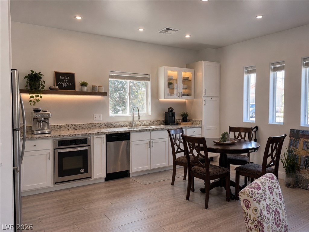 5446 Pine Ranch Street Las Vegas, NV 89113 - Photo 7 of 7 Recessed lighting illuminates this kitchen featuring stone counters, wood flooring, and clean cabinetry.