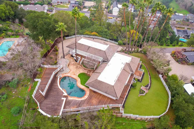 an aerial view of a house with swimming pool and outdoor seating