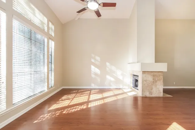 a view of empty room with wooden floor and fan