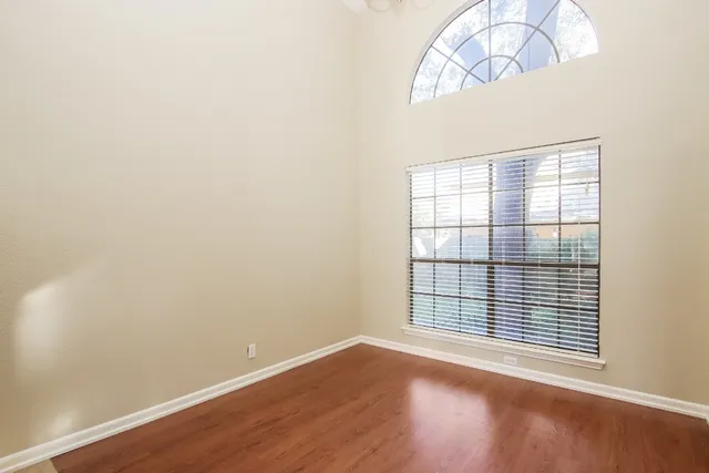 an empty room with wooden floor fan and windows