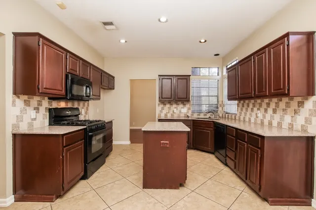 a kitchen with stainless steel appliances granite countertop wooden cabinets a stove top oven a sink and dishwasher