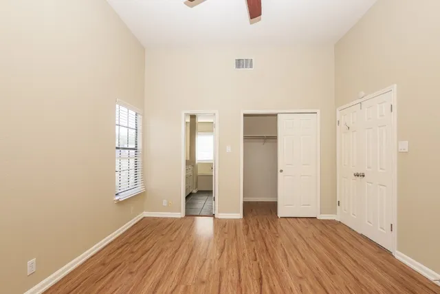 a view of an empty room with wooden floor and window