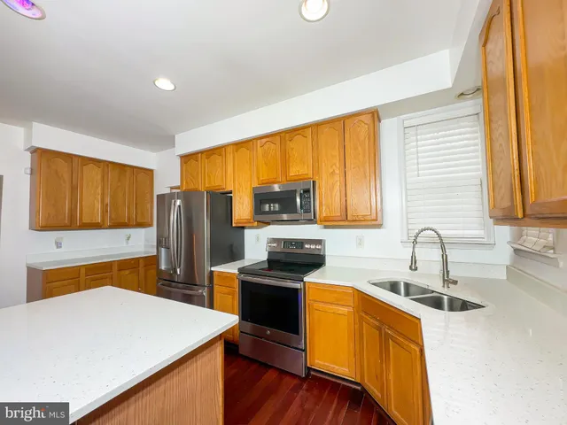 a kitchen with granite countertop a stove top oven a sink dishwasher and refrigerator with wooden floor