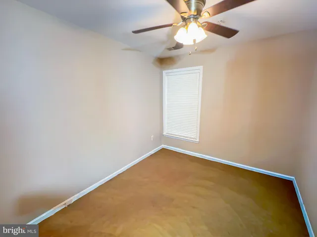an empty room with a chandelier fan and windows