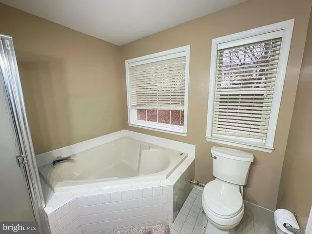 a white toilet sitting next to a window and a bathtub