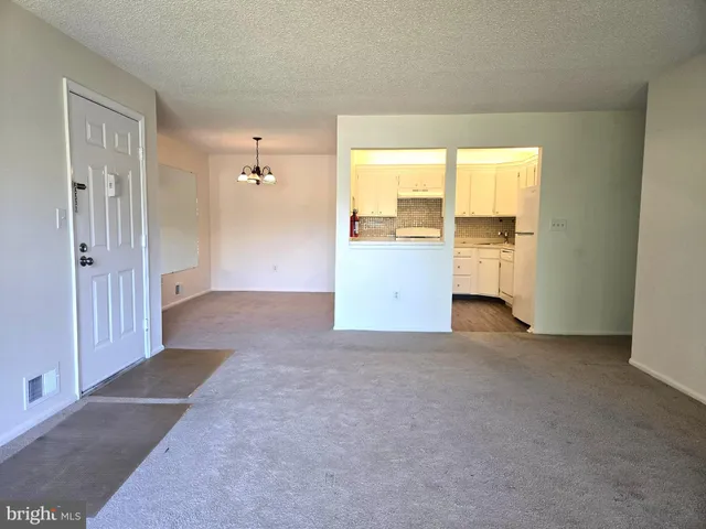 an empty room with a window and a kitchen view