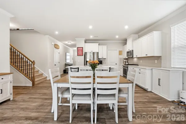 a kitchen with stainless steel appliances kitchen island granite countertop a table chairs sink and cabinets