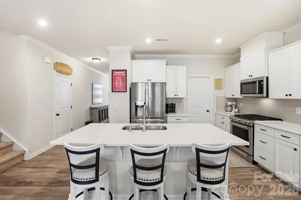 a kitchen with stainless steel appliances kitchen island granite countertop a kitchen island a stove a table and chairs