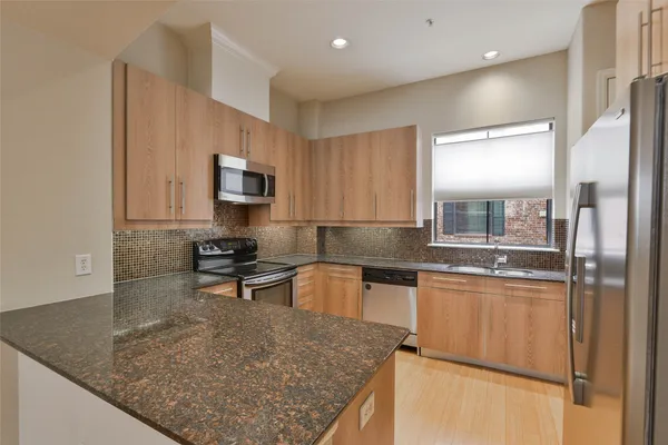a kitchen with stainless steel appliances granite countertop a sink stove and refrigerator