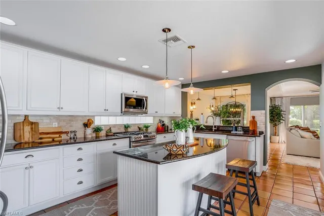 a kitchen with stainless steel appliances granite countertop a stove top oven a sink dishwasher and white cabinets with wooden floor