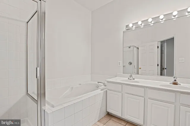 a bathroom with a double vanity sink mirror and bathtub