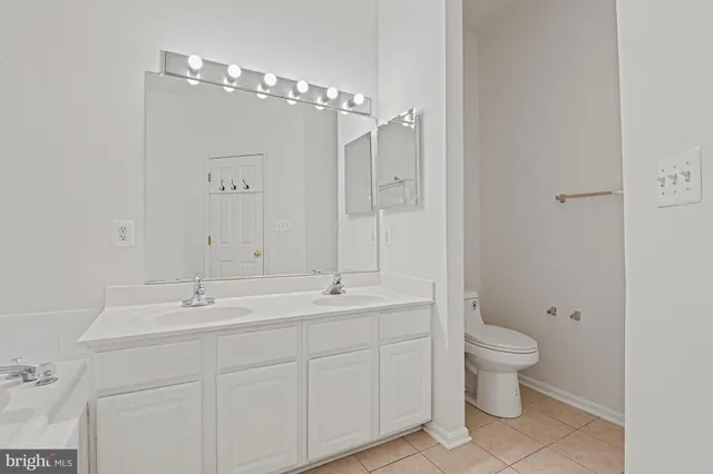 a spacious bathroom with a double vanity sink a toilet and a mirror