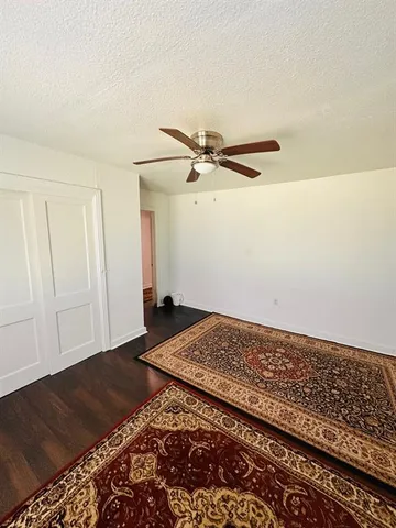 a view of a bedroom with wooden floor and a ceiling fan
