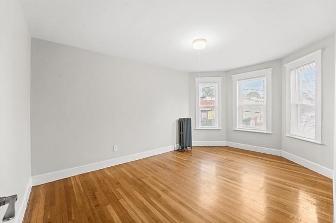 40 Ripley Road, Unit 2 Boston, MA 02121 - Photo 8 of 25 a view of an empty room with a window and wooden floor