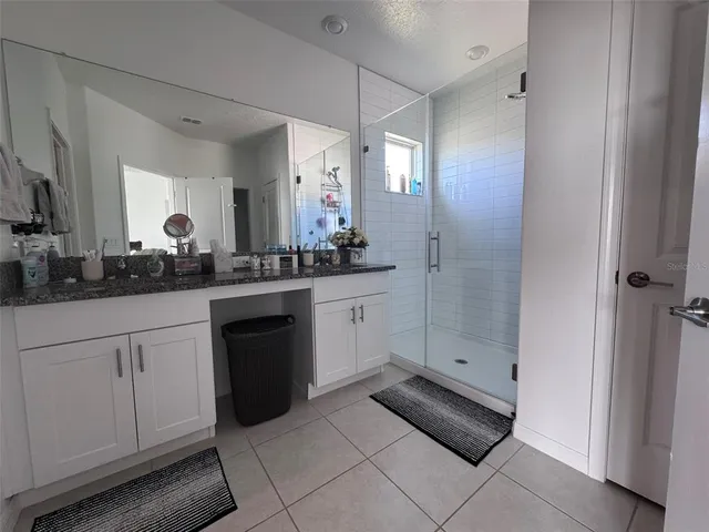 a bathroom with a granite countertop sink a shower and a mirror