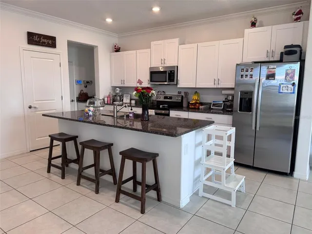 a large kitchen with stainless steel appliances granite countertop a sink stove and refrigerator