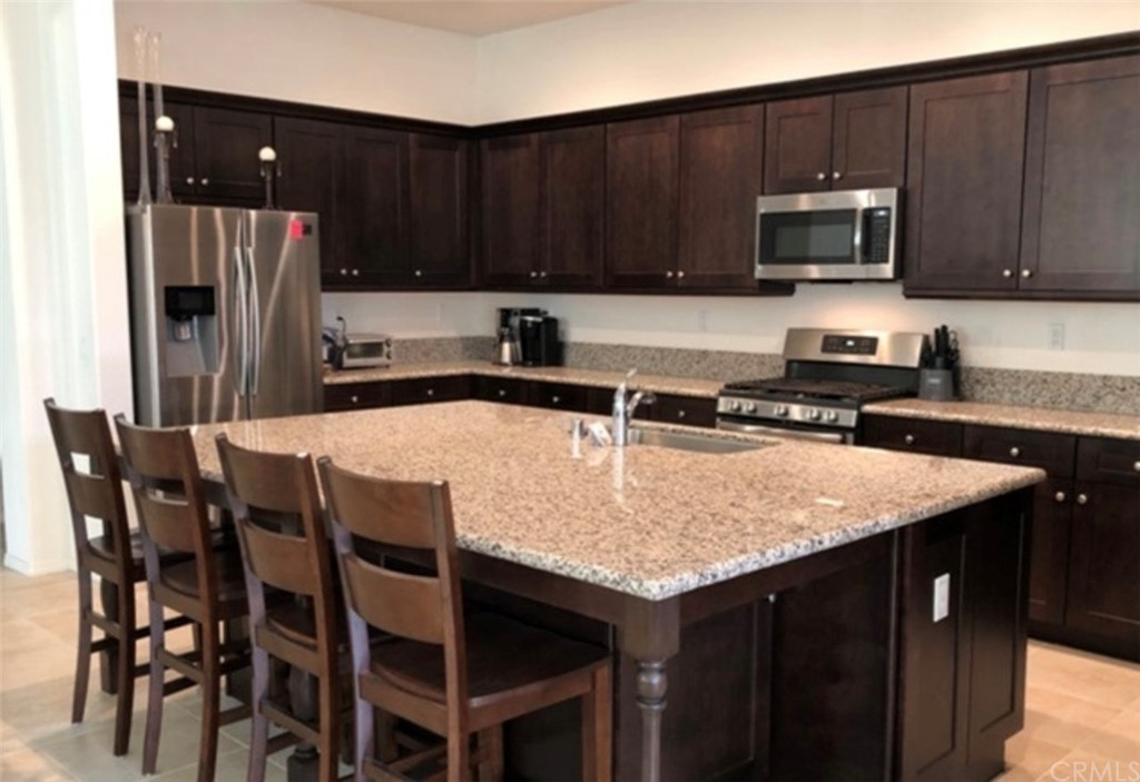 1603 Sams Canyon Beaumont, CA 92223 - Photo 2 of 18 a kitchen with stainless steel appliances wooden cabinets a stove a sink and a microwave