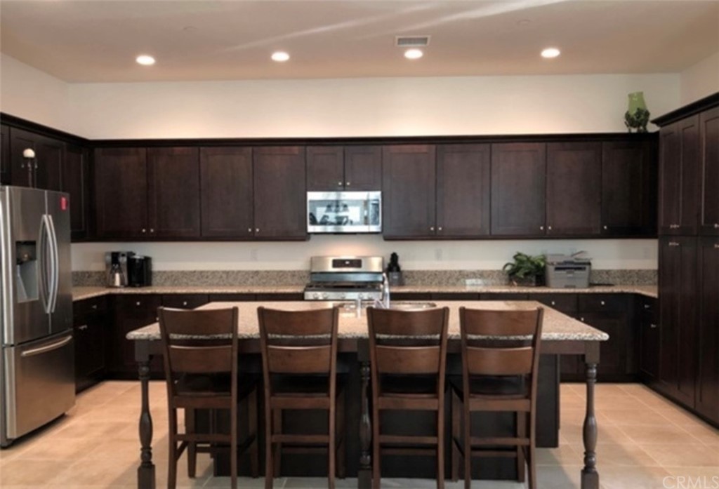 1603 Sams Canyon Beaumont, CA 92223 - Photo 3 of 18 a kitchen with stainless steel appliances wooden cabinets refrigerator dining table and chairs