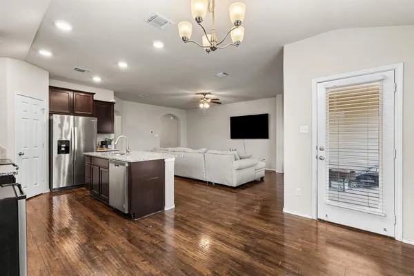a view of kitchen with stainless steel appliances kitchen island a stove a refrigerator a oven and a view of living room
