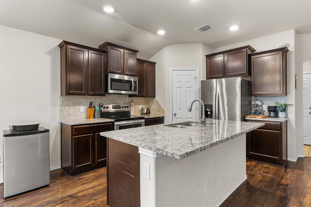 11233 Buzzard Gulch Drive Waco, TX 76708 - Photo 26 of 37 a kitchen with kitchen island granite countertop stainless steel appliances cabinets a sink and a refrigerator