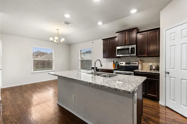 a large kitchen with granite countertop a large counter top cabinets appliances and a center island